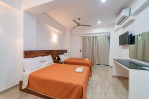 A hotel room with two beds, a ceiling fan, an air conditioning unit, a TV, and a sliding door leading to a balcony. - Mi Querida Maribel Hotel (Santa María Huatulco)