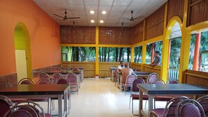 Un amplio comedor interior con techos altos, varias mesas y sillas, y grandes ventanales que dejan entrar luz natural.