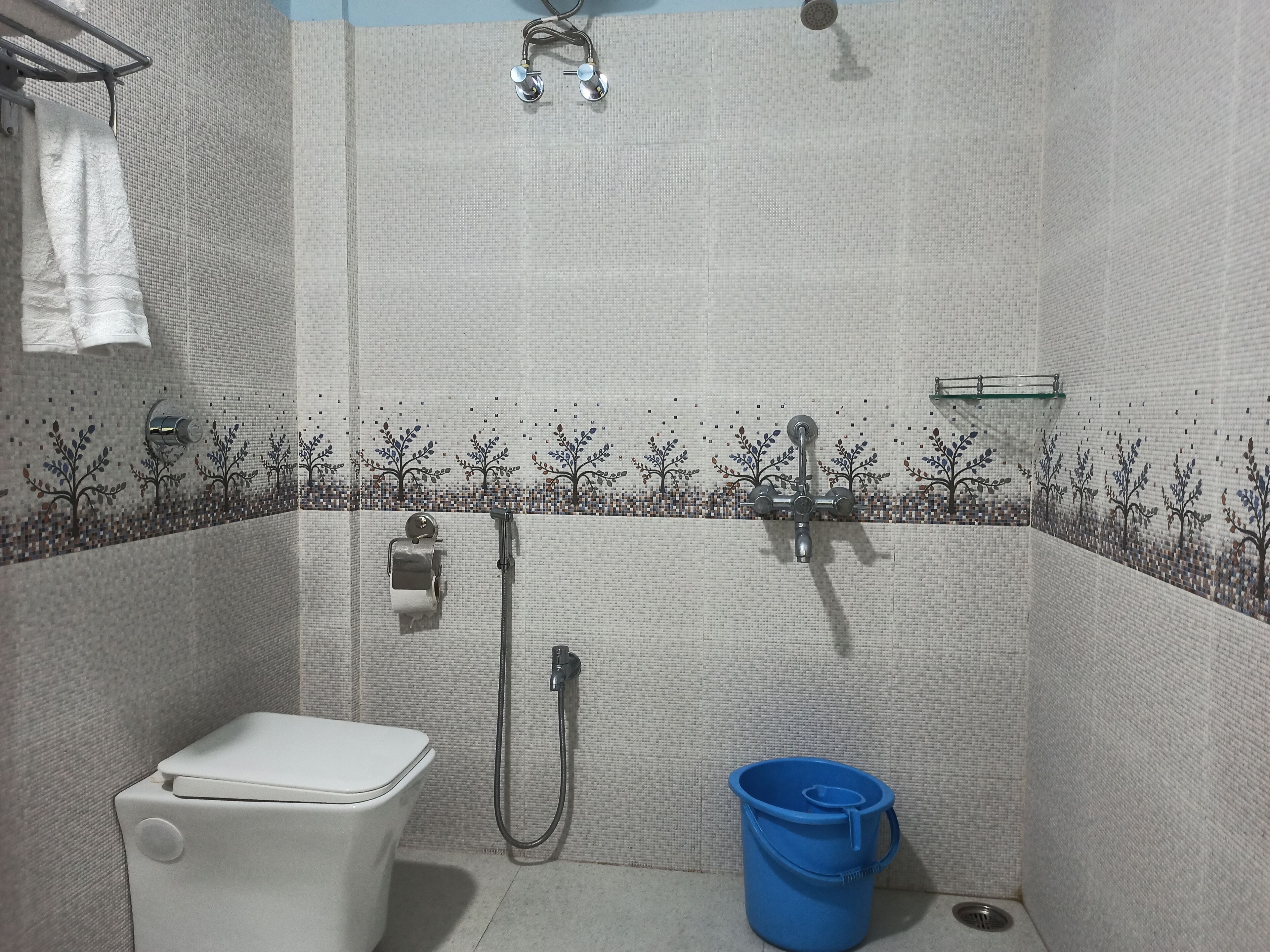 Un baño con inodoro, ducha y un cubo azul.