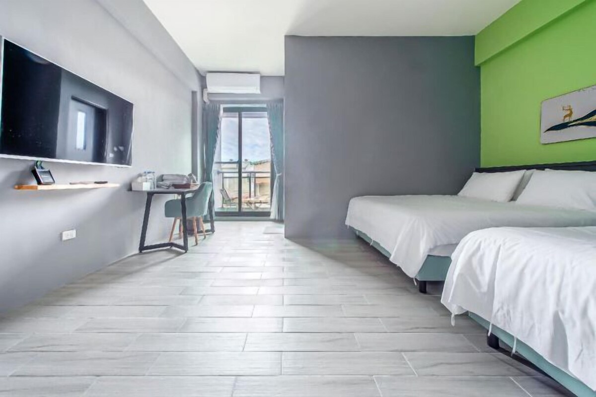 Una habitación de hotel moderna con una cama grande, un escritorio con silla, un televisor de pantalla plana en la pared y vistas a través de un ventanal.