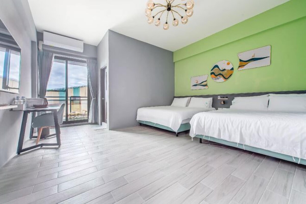 A modern hotel room with two beds, a dining area, and a balcony with a view.