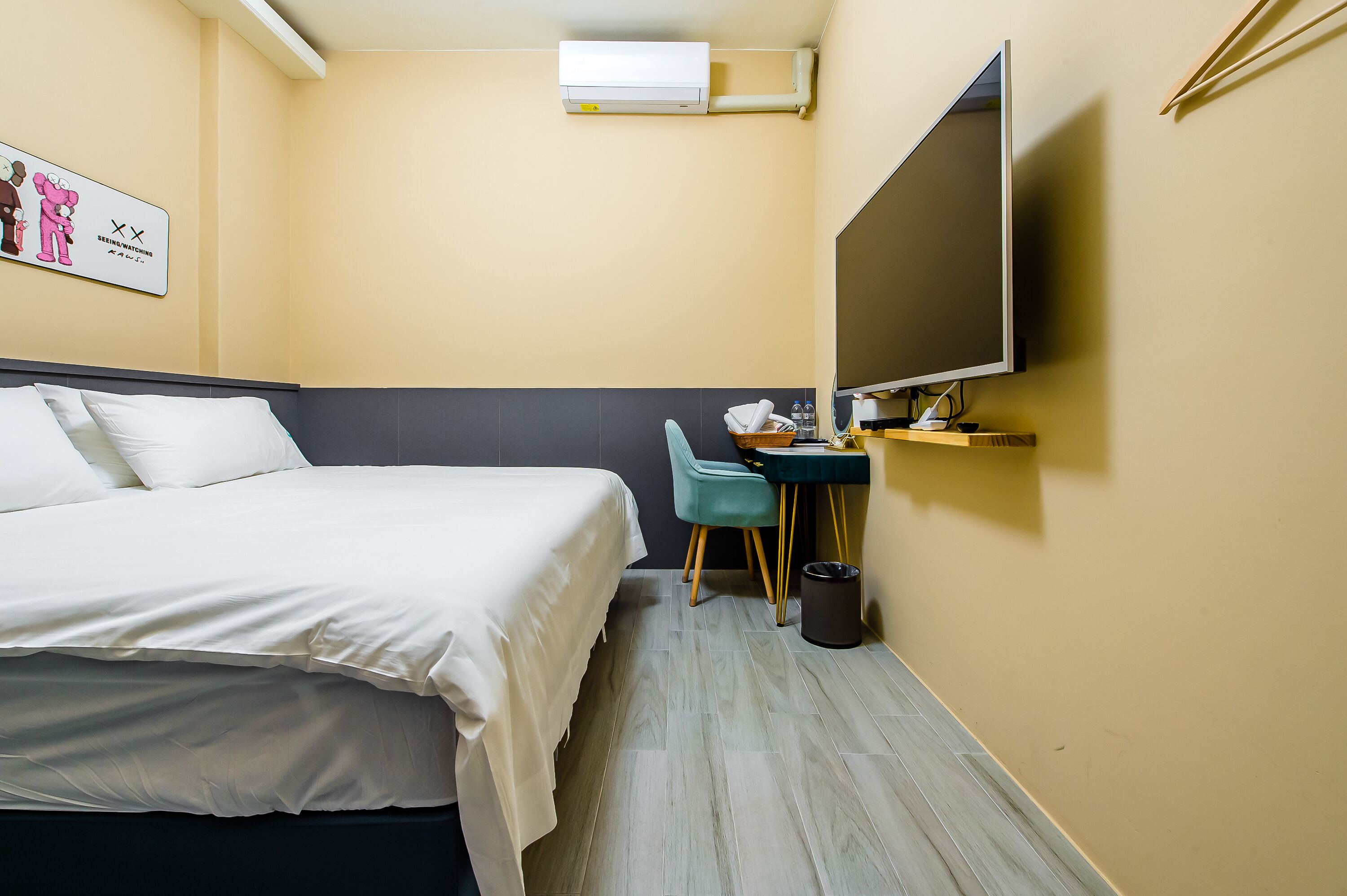 Habitación de hotel con cama, escritorio con silla, televisión de pantalla plana y cesto de basura.