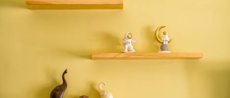 Three wooden shelves against a yellow wall, each holding various decorative items.
