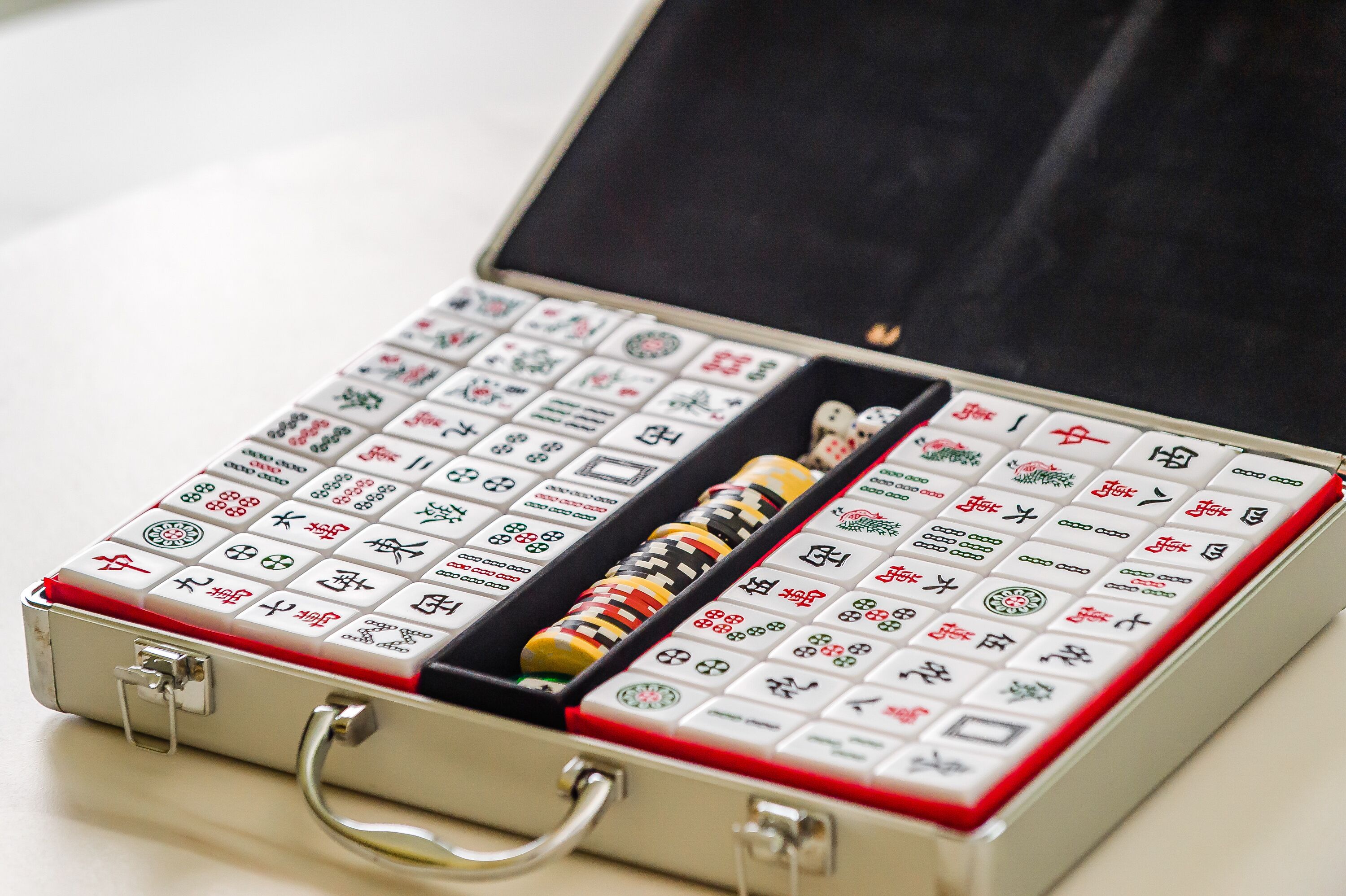 A mahjong set in a metal case with a red interior lining.