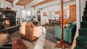 A spacious living room with a fireplace, a television, and a dining area with wooden furniture.