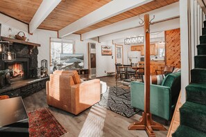 Uma sala de estar ampla com lareira, televisão e área de jantar com mobiliário de madeira.