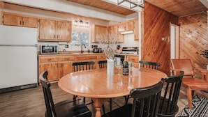 A modern kitchen with wooden cabinets, a dining table with chairs, and a chandelier.