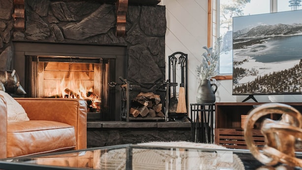 A cozy living room with a stone fireplace, a leather sofa, and a glass coffee table.