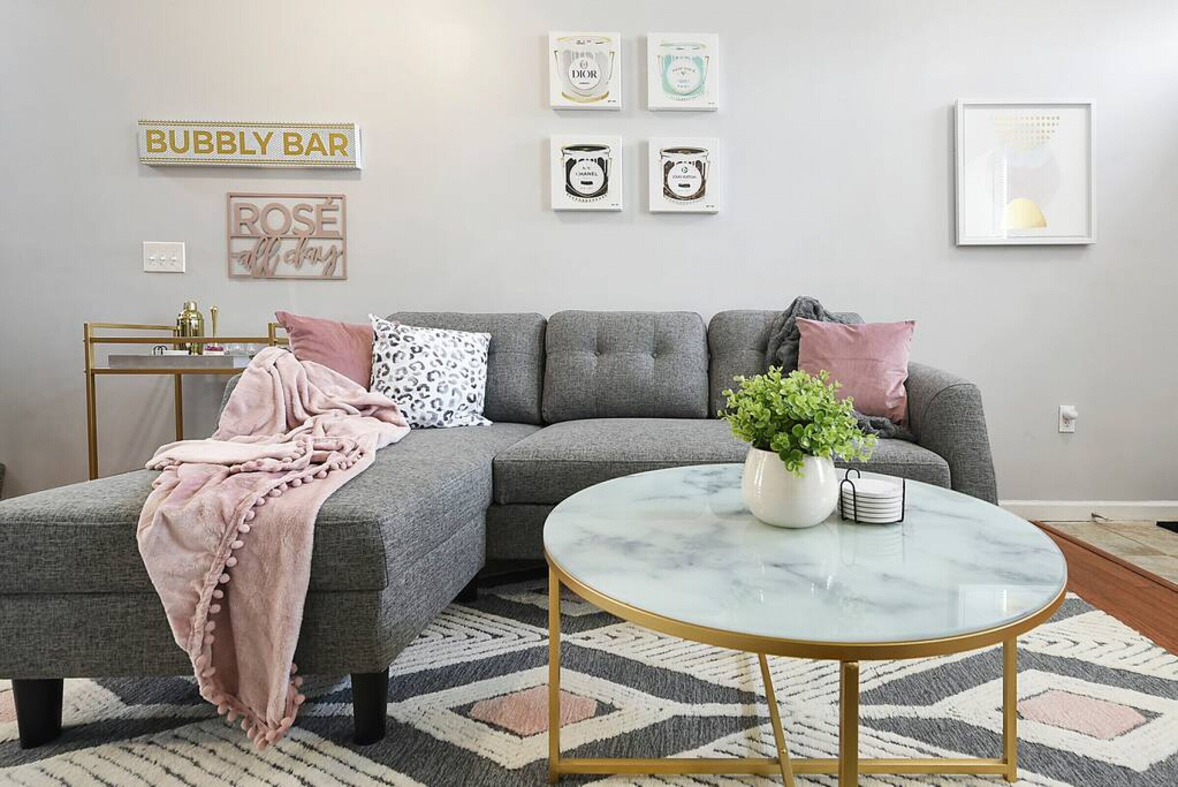 Una sala de estar con un sofá seccional gris, una mesa de centro redonda y una alfombra estampada.