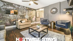 A modern living room with a ceiling fan, a coffee table, and two sofas. There is a wall with chalkboard writing and a television. - M&J - 823 James St. (Pittsburgh)