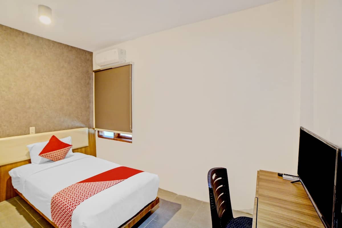 A hotel room with a bed, a desk, a chair, and a TV.