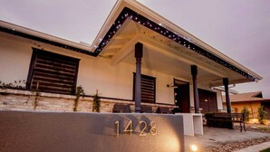 A modern house with a stone facade, a covered porch, and a well-lit entrance.