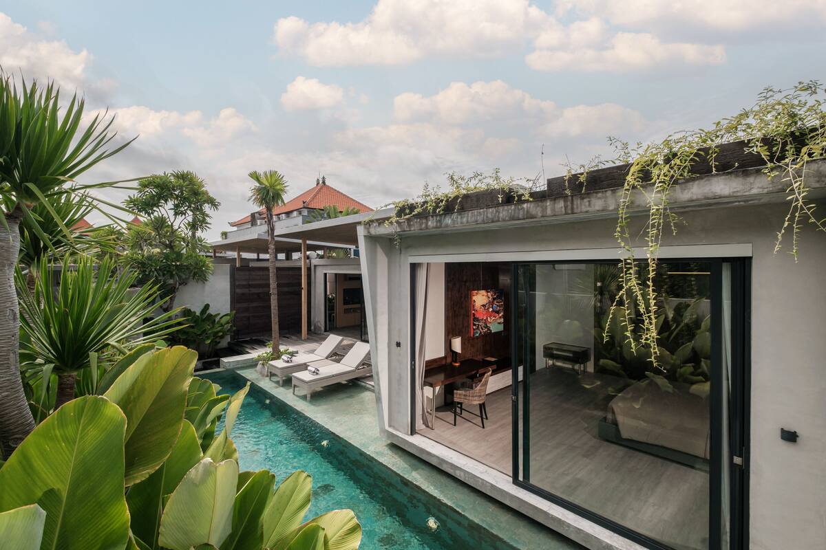 A modern house with a swimming pool, a dining area, and a lounge with chairs.