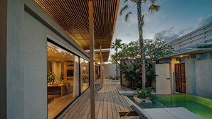 A modern outdoor area with a wooden deck, lounge chairs, and a swimming pool.
