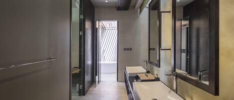 A modern bathroom with a long mirror, two sinks, and a wooden floor.