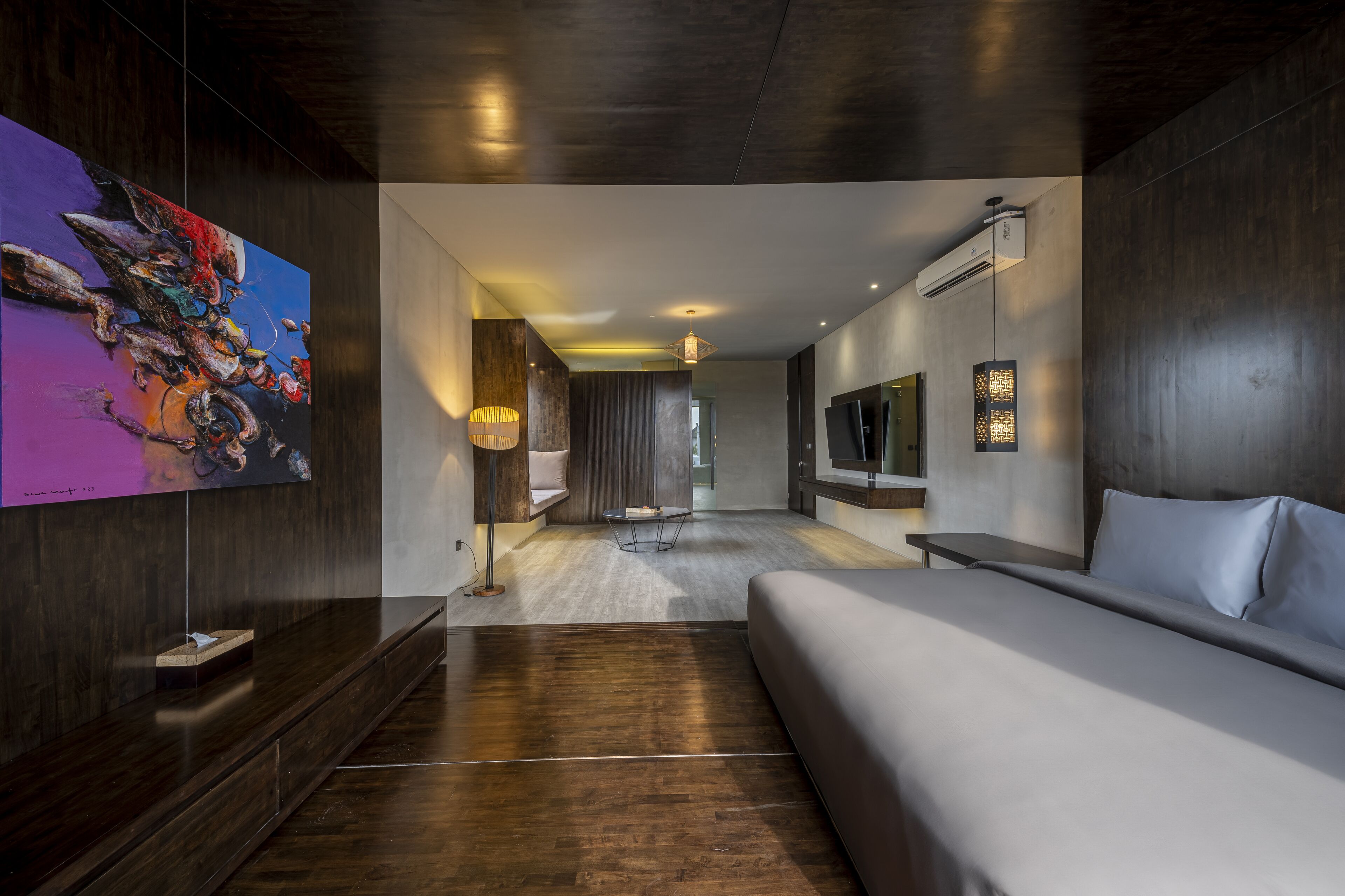 Una habitación de hotel moderna con una cama grande, un televisor de pantalla plana y un cuadro en la pared.