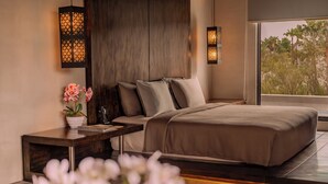 A modern bedroom with a large bed, a nightstand, a potted plant, and two wall-mounted lights.