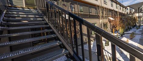 A staircase with metal railings leading to a building with multiple windows and a snow-covered ground.