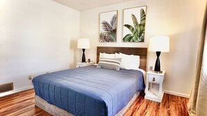 A hotel room with a large bed, two bedside tables, and two wall-mounted lamps. - Blue House Cozy Getaway (Sioux Falls)