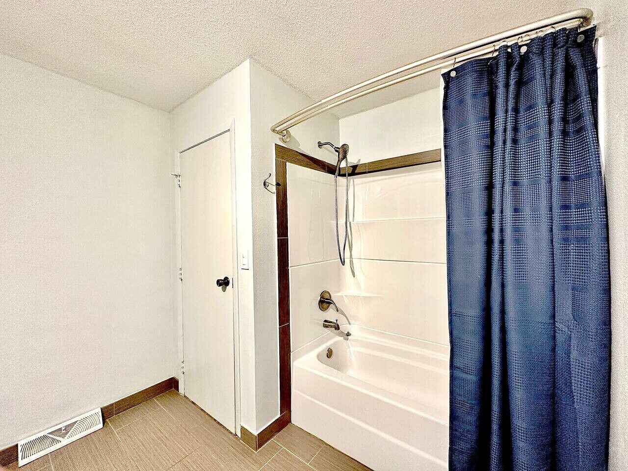 A bathroom with a bathtub, shower, and a door.
