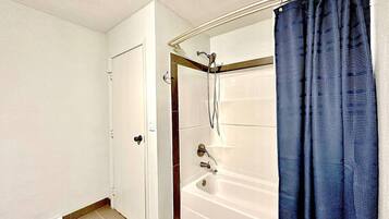 A bathroom with a bathtub, shower, and a door.