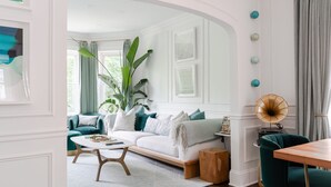 A modern living room with a white sofa, teal armchairs, and a coffee table. - Classic Chicago 2 Flat transformed into a Parisian plant lovers paradise (Chicago)