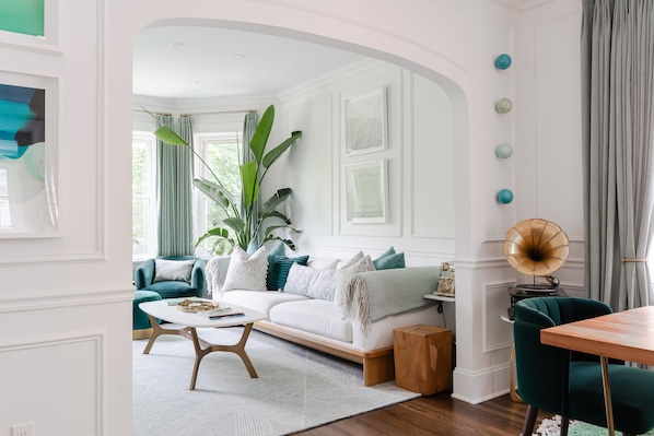 Una sala de estar moderna con un sofá blanco, sillones turquesa y una mesa de centro.