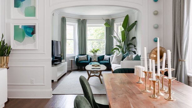 A modern living room with a wooden dining table, green sofas, and a large window with curtains. - Classic Chicago 2 Flat transformed into a Parisian plant lovers paradise (Chicago)