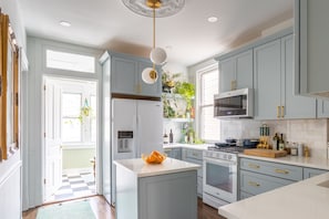 Una cocina moderna con armarios azul claro, una isla central y una lámpara colgante.