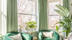 A room with two teal armchairs, a matching ottoman, and a large potted plant. - Classic Chicago 2 Flat transformed into a Parisian plant lovers paradise (Chicago)