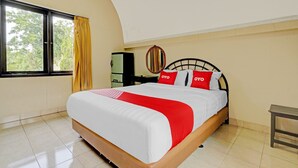 Habitación de hotel con una cama grande, una ventana con cortinas, una mesita de noche y un armario.