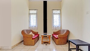 Una habitación con dos sofás de mimbre con cojines rojos, una mesita de madera y una mesa negra.