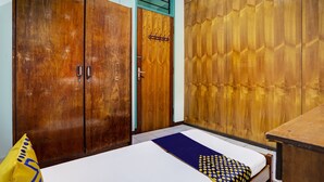 Una habitación con cama, armario de madera y una mesita.