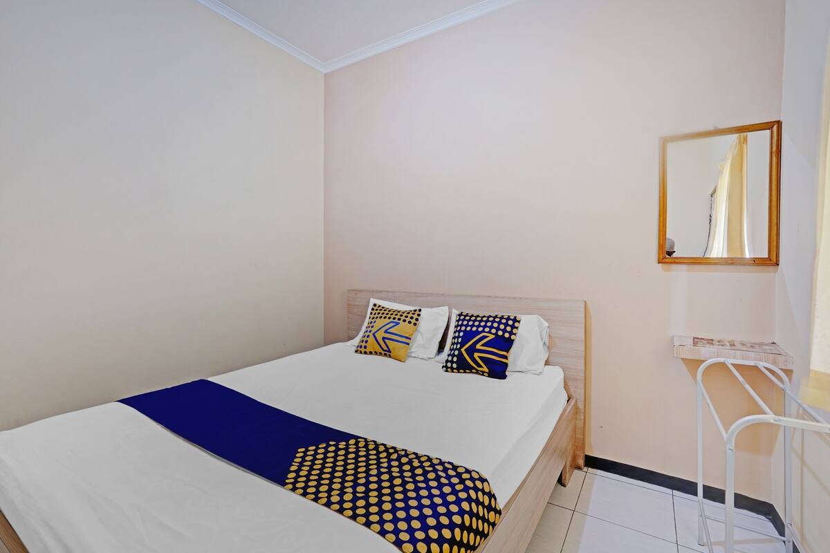 A neatly made bed with a blue and yellow patterned blanket, two pillows with geometric designs, and a wooden headboard.