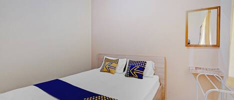 A neatly made bed with a blue and yellow patterned blanket, two pillows with geometric designs, and a wooden headboard.