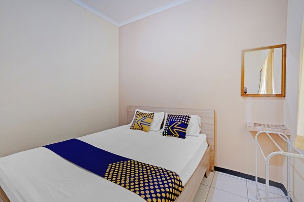 A neatly made bed with a blue and yellow patterned blanket, two pillows with geometric designs, and a wooden headboard.
