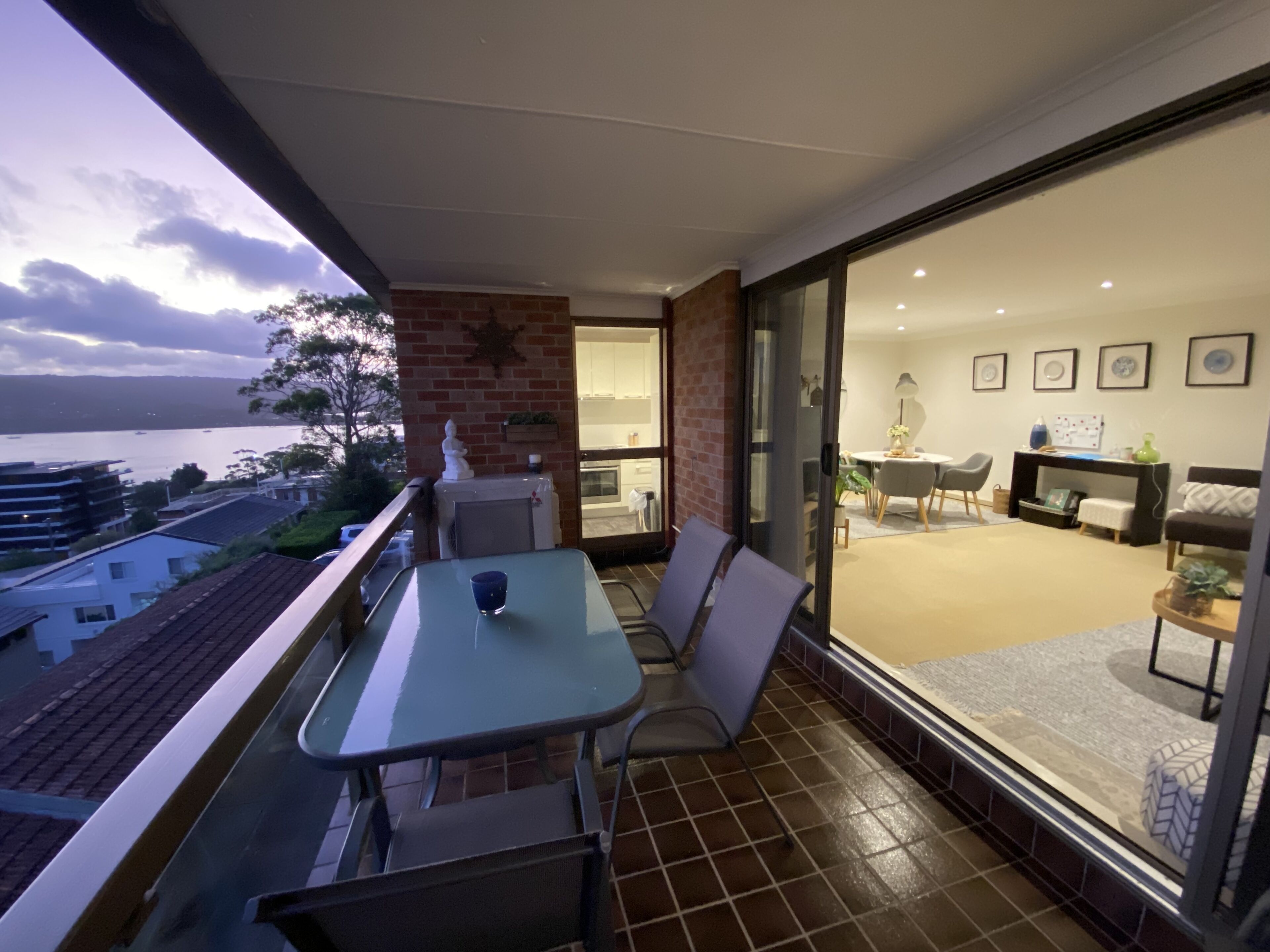 Un balcon avec une table et des chaises, une vue sur la mer et un aperçu de l’intérieur, notamment de l’espace repas.