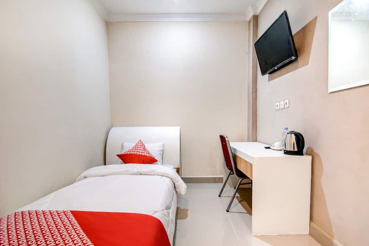 Une chambre d’hôtel équipée d’un lit, d’un bureau, d’une chaise, d’une télévision et d’une machine à café.