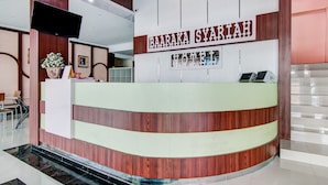 Un comptoir d’accueil d’hôtel avec une pancarte indiquant : « HÔTEL BAARAKA SYARIAH ».
