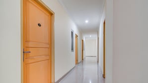 Un couloir avec des portes en bois, des murs blancs et un sol carrelé.
