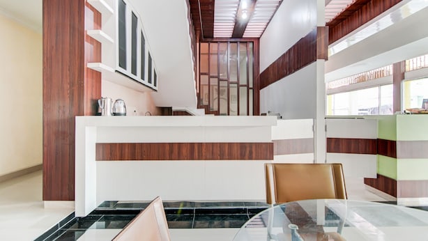 Un intérieur moderne comprenant un comptoir d’accueil, un escalier et un coin repas avec une table en verre.