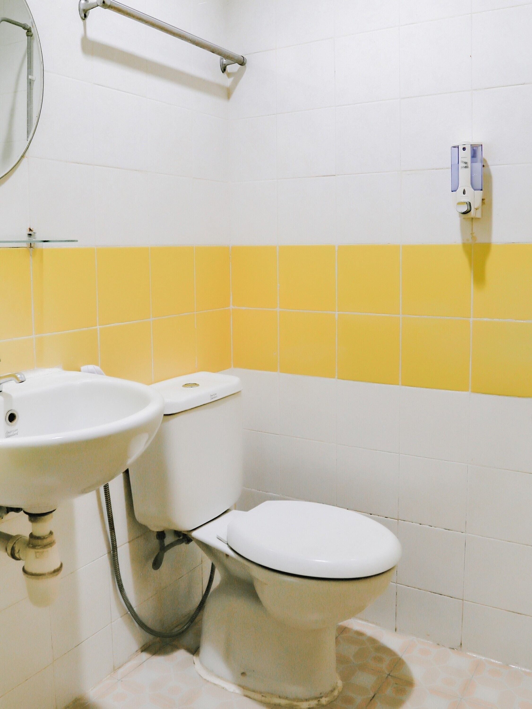A bathroom with a white sink, toilet, and yellow-tiled wall.