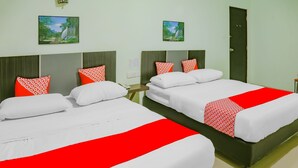 A hotel room with two beds, each with white bedding and red accents, a small bedside table, and a door. - OYO 90269 Hotel Indorasa 2 (Batam)