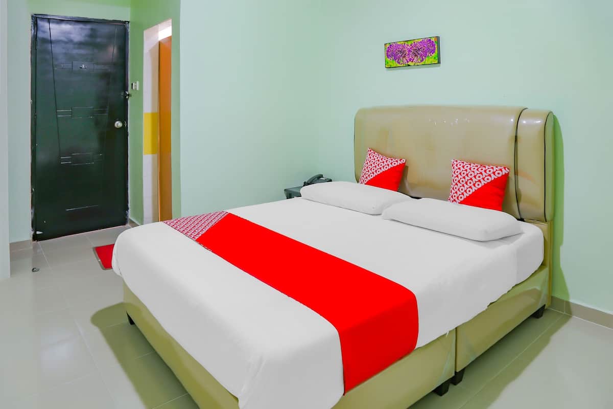 Een hotelkamer met een bed, nachtkastje, telefoon en een deur.