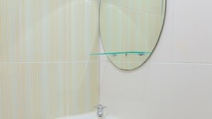 A bathroom with a white sink, a mirror, and striped wall tiles. - OYO 90269 Hotel Indorasa 2 (Batam)
