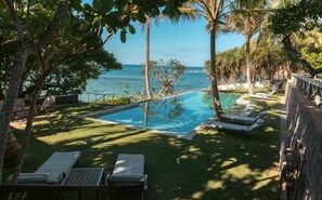 A pool area with lounge chairs, a small table, and a view of the ocean. - Elevated Family Beach Villa Overlooking Surf Break (Weligama)