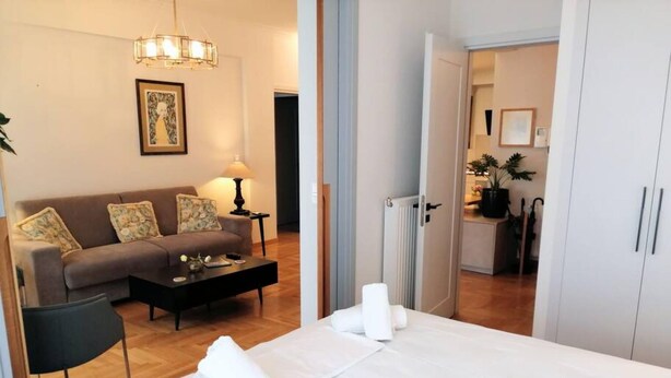 Une chambre d’hôtel avec un lit, un canapé, une table basse, une lampe et un tableau au mur.
