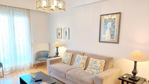 Un salon avec un canapé beige, une table basse, une lampe et une œuvre d’art encadrée accrochée au mur.