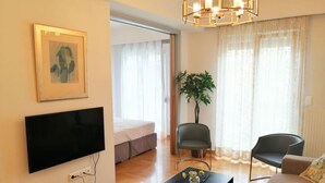 Un salon moderne comprenant un téléviseur à écran plat, un canapé, deux fauteuils, une table basse et une plante.