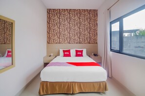 A hotel room with a bed, a nightstand, a mirror, and a window. - OYO 90312 Bahu Bay Hotel (Manado)